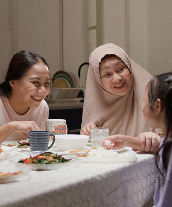 Malay family talking happily while eating dinner